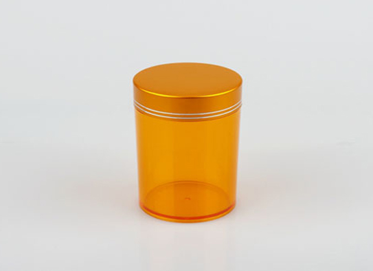 Durchsichtige orangefarbene Kunststoffflasche mit einer Aluminiumschraube